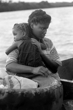 A young girl clings to her mother prior to disembarking from a boat after crossing the Gulf of Uraba. They are to join a 'Peace Community', a settlement of people who were exiled by a joint military/p...