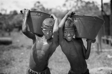 Two boys carry buckets of water in the 'Peace Community' of Cacarica. The community is a settlement of people who were displaced by a joint military/paramilitary offensive, named Operation Genesis, in...