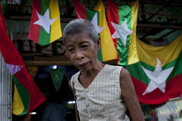 A homeless woman walks past new Burmese flags on sale in a shop in Yangon. The Burmese government introduced the new flag in the lead up to the elections scheduled for 07/11/2010.
