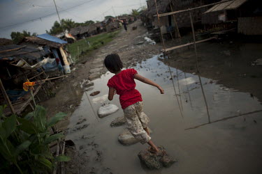 A child walks across stepping-stones in a puddle of stagnant water in the Hlaing Thaya slum district of Yangon.