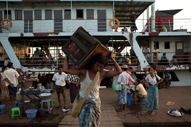 A labourer unloads a box from a passenger ferry at the Rangoon (Yangon) River docks.