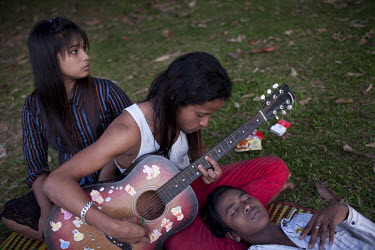 University students relax and play a guitar by a lake in Rangoon (Yangon).