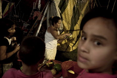 Elizabeth (centre), the wife of the circus owner prepares mango biche, a bitter unripe mango for the performers at the Jhon Danyer Circus during the interval. Around a dozen small circuses wander the...