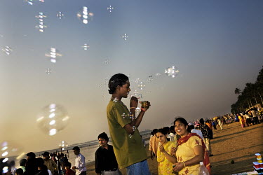 A young man blows bubbles on Juhu Beach in the upscale Bandra area of Mumbai, a popular walking spot among the middle class.