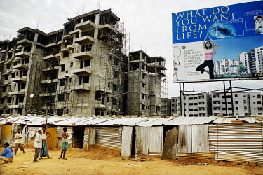 Migrant workers outside their temporary housing beside the construction site of a new luxury apartment enclave.