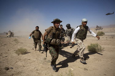 Afghan National Army (ANA) soldiers and a US Army medic from Charlie Company, Sixth Battalion, 101st Aviation Regiment carry a wounded soldier on to a waiting medevac helicopter after his vehicle hit...