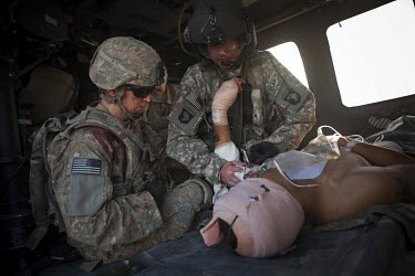 US Army soldier Staff Sgt. Andrew Jennings, Company C, 2nd Battalion, 508th Parachute Infantry Regiment (left) consoles his comrade while being treated on board a medevac helicopter from Charlie Compa...