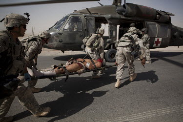 US Army soldiers load their wounded comrade onto a medevac helicopter from Charlie Company, Sixth Battalion, 101st Aviation Regiment after he was injured in an IED (improvised exlosive device) blast w...