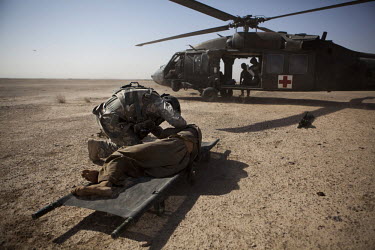 Sgt Shields, a medic from Charlie Company, Sixth Battalion, 101st Aviation Regiment treats a wounded civilian next to a US Army medevac helicopter after his vehicle hit an IED (improvised explosive de...