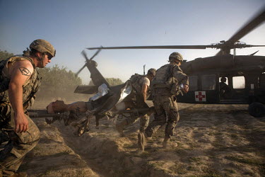 US Army soldiers load a wounded soldier onto a waiting medevac helicopter from Charlie Company, Sixth Battalion, 101st Aviation Regiment in the middle of a firefight near Kandahar. The wounded soldier...