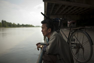 A man smokes a cigarette on a river bank after a days fishing in Pyongyang.