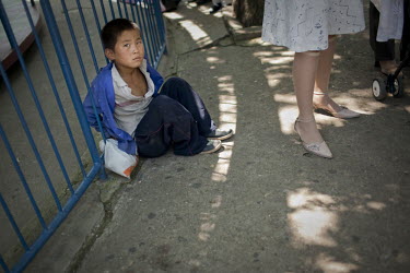 A child begs on the street as people attend a fun fair in Pyongyang.