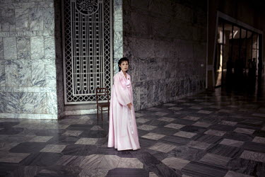 An usher wearing a colourful dress stands in the foyer of a theatre during an acrobatics performance in Pyongyang.