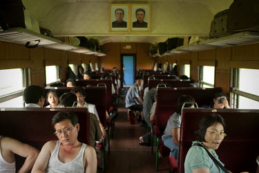 Passengers sit on a train as they are watched over by portraits of Supreme Leader Kim Jong-il (right) and Eternal President Kim II-sung (left) near Pyongyang.