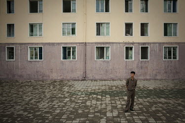 A man stands in front of an apartment block in Pyongyang.