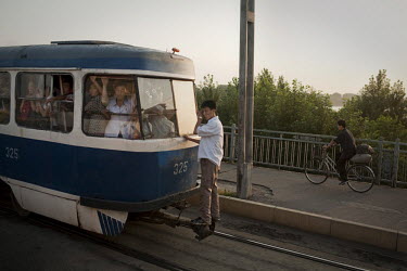 A man hangs on as he rides on the back of a train in Pyongyang.