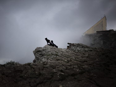 A tourist leans over the edge of the Ai-Petri mountains looking towards Yalta.