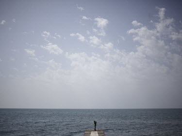A child stands on the end of a pier looking out over the Black Sea at Artek, a youth camp in Gurzuf.