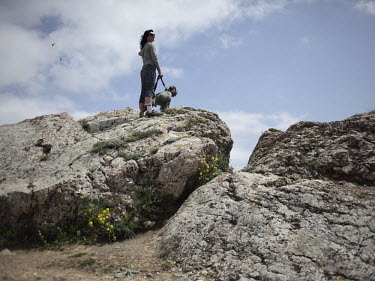 A tourist stands on a rock with her dog as she looks out over the Black Sea.