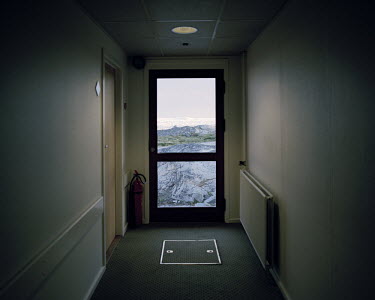 The emergency exit door of a luxury hotel. Icebergs can be seen through the window of the door.