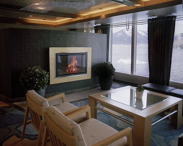 A room on a luxury cruise liner as it passes through Uummannaq Bay. A video of a log fire is on the television screen.