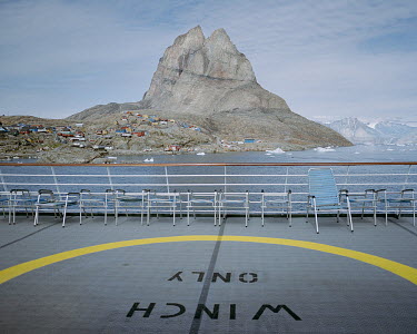 A luxury cruise liner passes the town of Uummannaq with the Uummannaq Mountain in the background.
