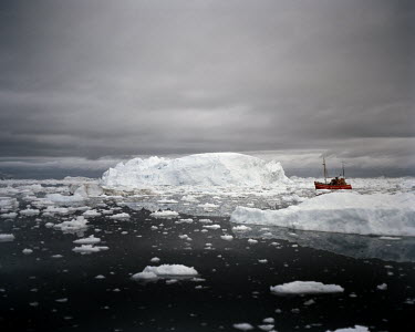 A fishing boat makes its way past icebergs produced by the Ilulissat Glacier, a UNESCO World Heritage Site.
