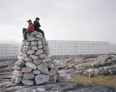 Children sit on a pile of stones in a poor residential area in Nuuk.