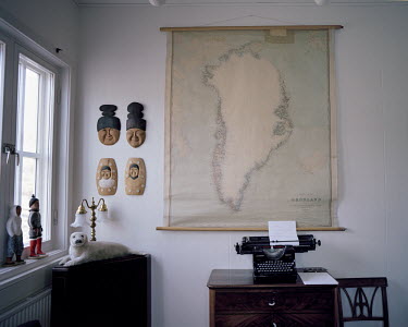 An old map of Greenland behind a typewriter and next to Inuit artefacts in a house in Uummannaq.