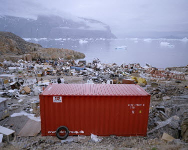 A Danish rubbish container at a rubbish dump near the harbour at Uummannaq. In the background, pieces of ice float on the sea.