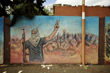 A mural of a man holding  a rifle and giving the two-fingered hand sign for 'victory' painted on a wall in the Gaza Strip.