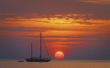 The sun sets behind a yacht moored off Kata Beach, near Phuket.