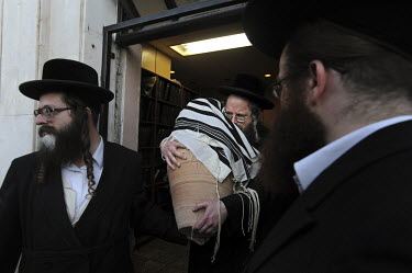 An Ultra-orthodox Jewish man carries a clay jar containing a burnt Torah scroll, during a burial ceremony for Torah scrolls that were destroyed in a fire.  Eleven Torah scrolls were burnt in a fire th...