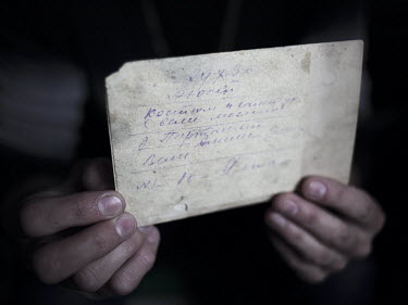 Jiliara shows the back of a photograph of her grandfather, the only surviving memento she has of him since his death after the deportation, at her house in Nikita, an unoffocial Tatar community.
