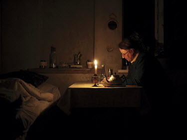 Elvira reads a book using the light of a candle in her house in Nikita, an unofficial Tatar community.