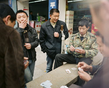 53 year old Yi Bai Quan (centre) and his friends smoke and play cards in Chongqing. They are known as 'bang bang men' - people who act as porters carrying goods all around the city.