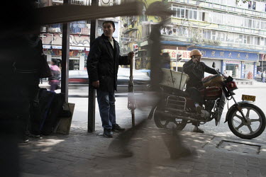 53 year old Yi Bai Quan holds a stick as he waits for work in Chongqing. Yi is known as a 'bang bang man' - people who act as a porters carrying goods all around the city.