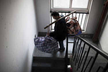 53 year old Yi Bai Quan walks down stairs carrying people's luggage in Chongqing. Yi is known as a 'bang bang man' - someone who acts as a porter carrying goods all around the city.