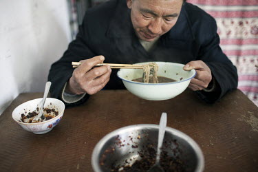 53 year old Yi Bai Quan eats lunch at his home in Chongqing. Yi is known as a 'bang bang man' - someone who acts as a porter carrying goods all around the city.