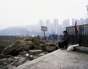 A woman sits near a construction site near the Yangtze River.