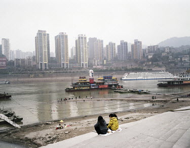 Two girls sit on the banks of the Yangtze River.