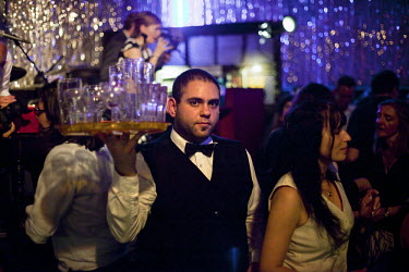 A waiter carries a tray of glasses across a crowded dance floor at Claerchen's Ballhaus. This old East Berlin ballroom has long been popular among the local working class residents but is in an area n...