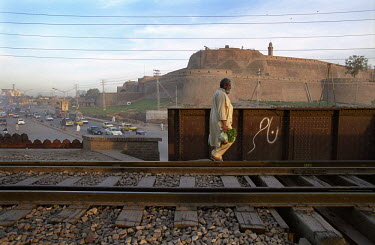 A man walks on a train line next to the Grand Trunk Road as it passes the Bala Hisar Fort in Peshawar, North-West Frontier Province built by the Sikhs in 1834 during their rule.