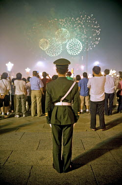 A military policeman watches fireworks illuminate the sky next to the entrance to the Forbidden City during the closing ceremony of the 2008 Beijing Olympic Games.