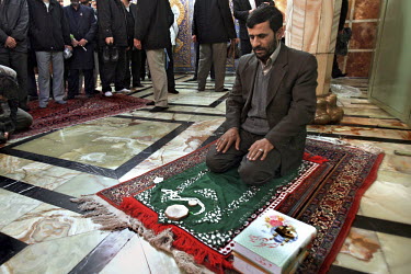 Iranian President Mahmoud Ahmadinejad sits kneeled saying the morning prayer in the holy city of Qom prior to a speech he is going to give to a crowd of locals.