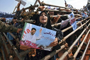 One of Iranian President Mahmoud Ahmadinejad's female supporters emerges from the barricades erected to keep people back, holding up a sign with the president's image on it, in the ethnic Turkish city...