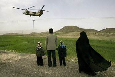 A family from the Iranian city of Shiraz watch as a helicopter carrying President Mahmoud Ahmedinejad to one of his provincial visits lands.
