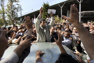 Iranian President Mahmoud Ahmadinejad stands surrounded by supporters after Friday prayers in Tehran; he holds request letters that have been stuffed into his hand by people in the crowd.