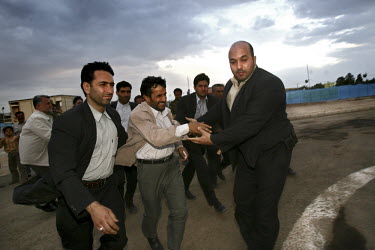Iranian President Mahmoud Ahmadinejad's bodyguards guide the diminutive leader towards his helicopter after a speech delivered in the city of Arak.