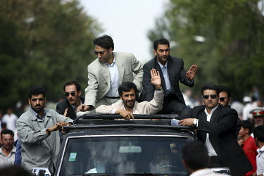 President Mahmoud Ahmadinejad waves from his armoured Nissan jeep with gun-carrying bodyguards hanging on to all sides of the car, as he is driven to deliver a speech in the central Iranian town of Is...